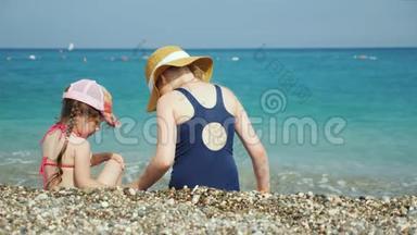 两个女孩坐在海边的小<strong>石子</strong>上，寻找美丽的小<strong>石子</strong>。海上儿童度假概念